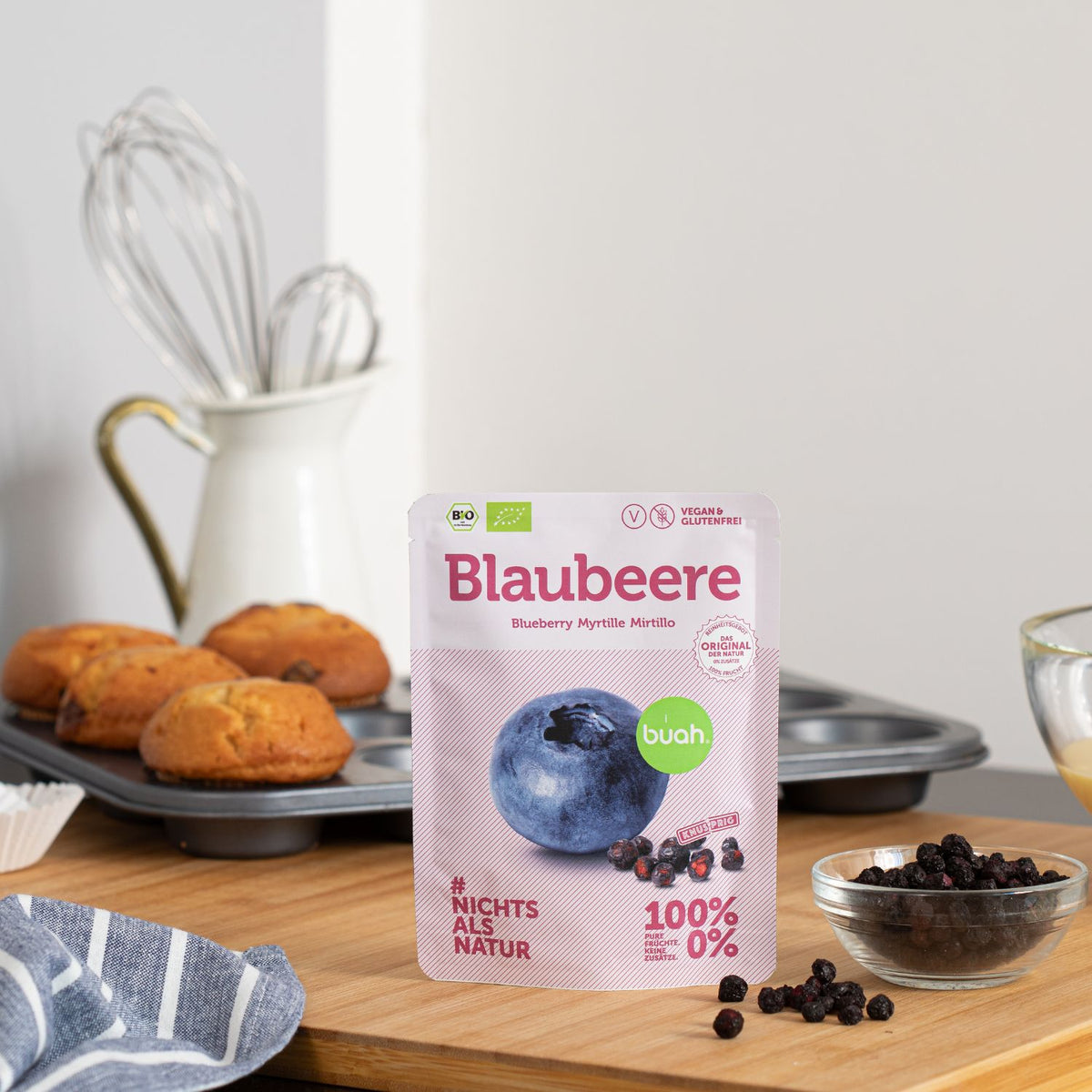 buah Blaubeere Snackpack auf Tisch neben frisch gebackenen Muffins mit Blaubeeren