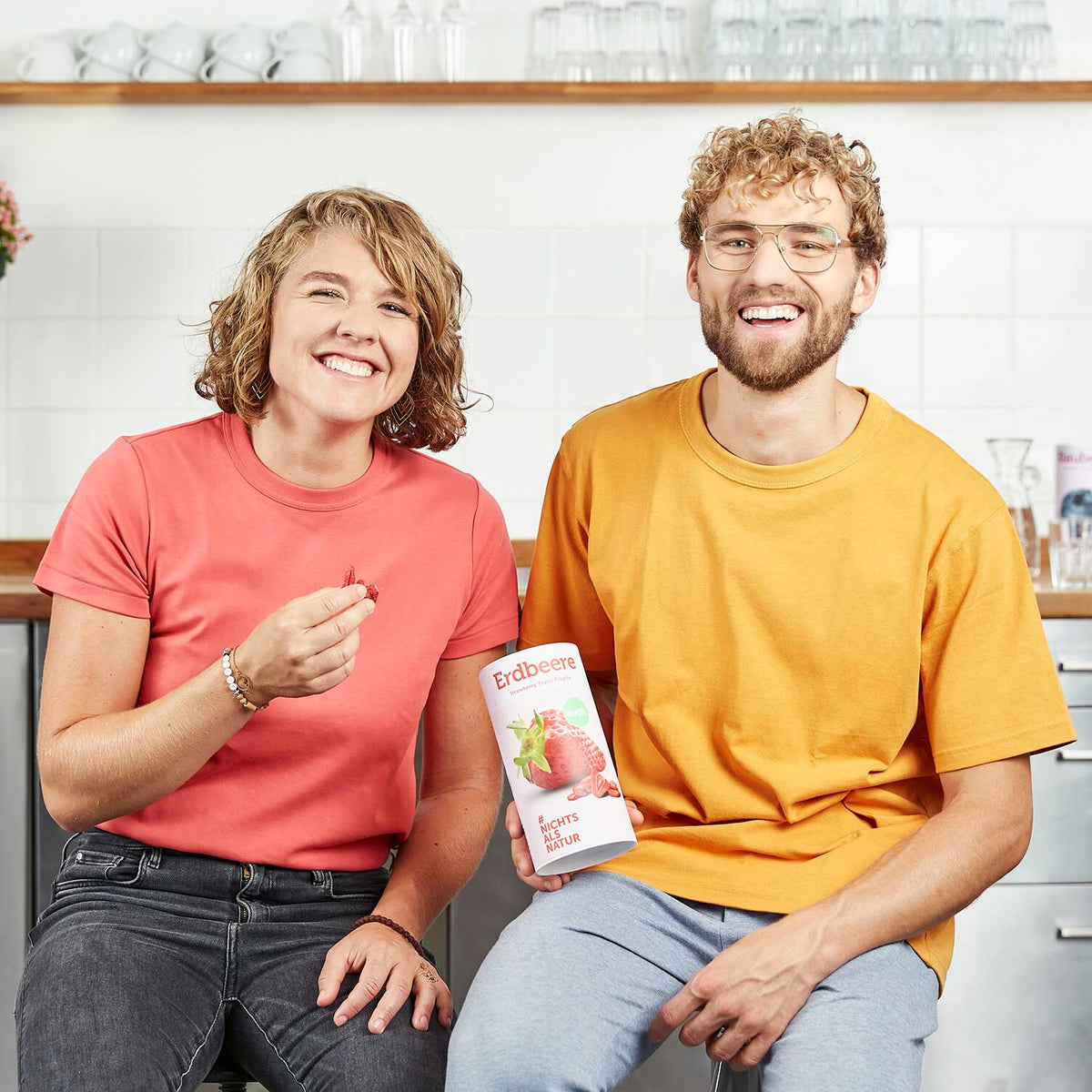 buah Gruender Jessica und Daniel Krauter lachen in Kamera mit Dose buah Erdbeeren
