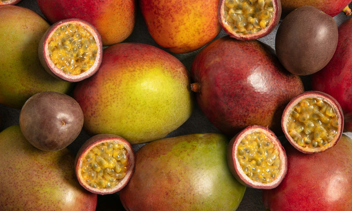 Viele frische, halbierte Maracujas und frische, rote Mangos neben und aufeinander