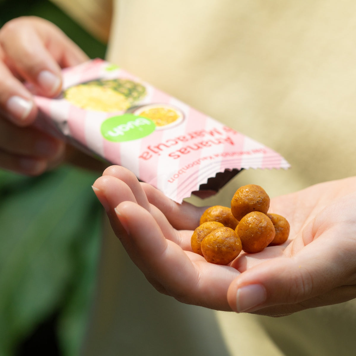 Kleine, runde und gelbliche Ananas-Maracuja Kaubonbons liegen in der offenen Hand einer Person