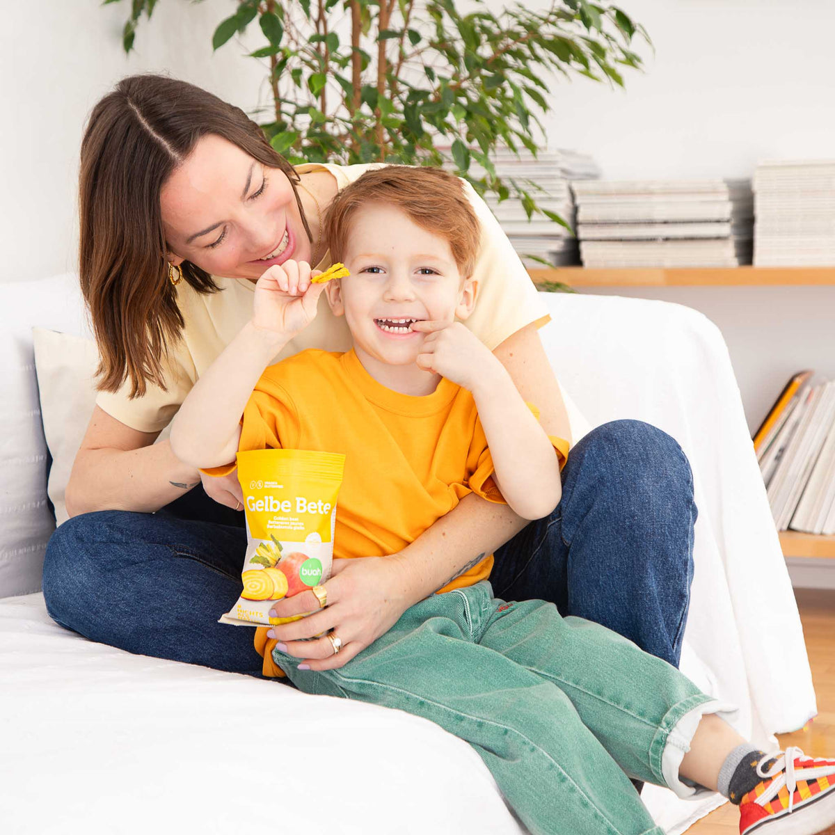 Mama und Sohn auf einem Sofa essen Gelbe Bete biuah.comips