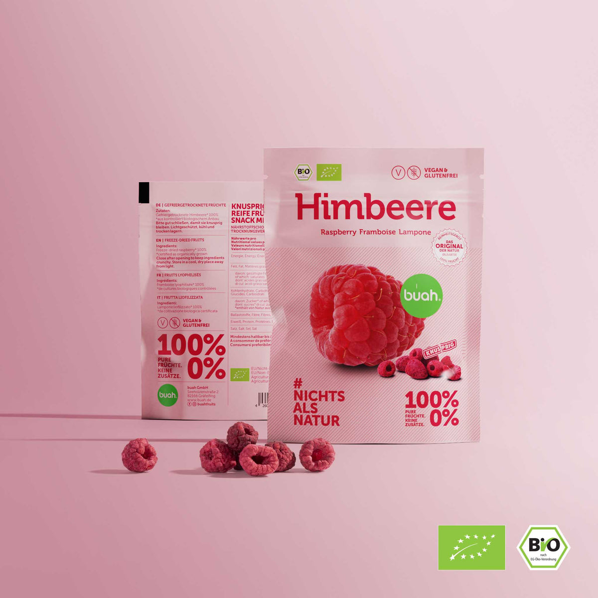 Zwei buah Snackpacks stehen nebeneinander mit gefriergetrockneten Himbeeren vor rosa Hintergrund