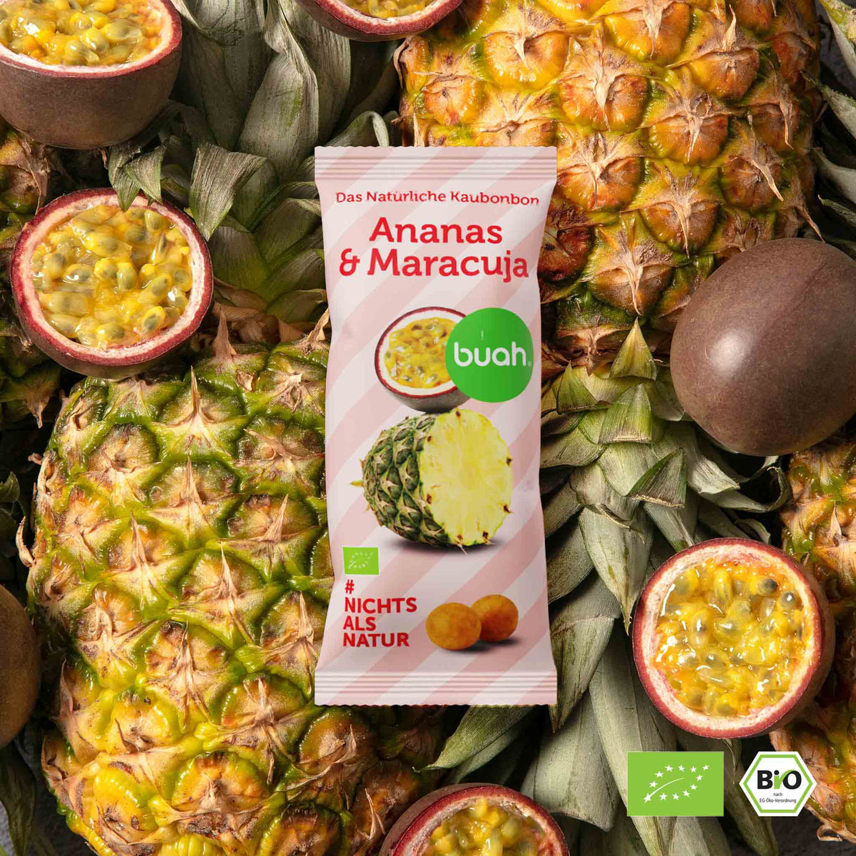 buah Ananas-Maracuja Kaubonbon Verpackung liegt auf frischen Ananas und halbierten Maracuja