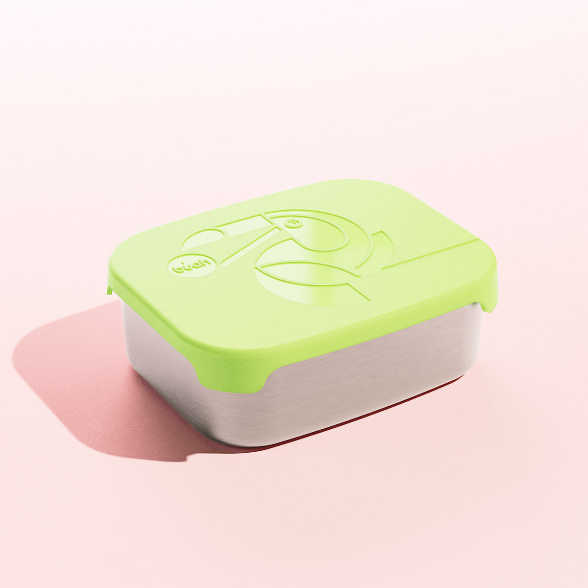 Neue buah Lunchbox aus Edelstahl mit hell-gruenem Deckel aus Silikon auf dem ein Tukan abgebildet ist der ein buah Kaubonbon im Schnabel hat. Bild vor rosa Hintergrund. 